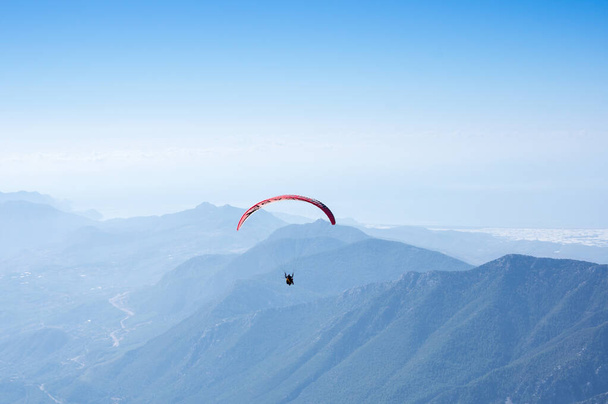 Paraglider flying over mountains near Kemer, a seaside resort on the Turkish Riviera in Antalya Province, Turkey - Foto, imagen