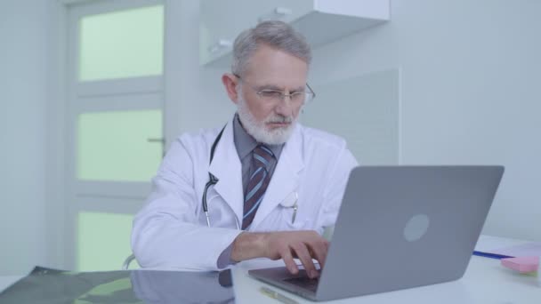 Senior doctor checking brain mri scan, typing diagnosis on laptop, medicine - Filmagem, Vídeo