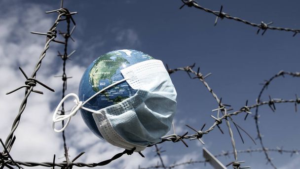 coronavirus global fight concept - COVID-19 - surgical mask, globe, wired fence - Photo, Image