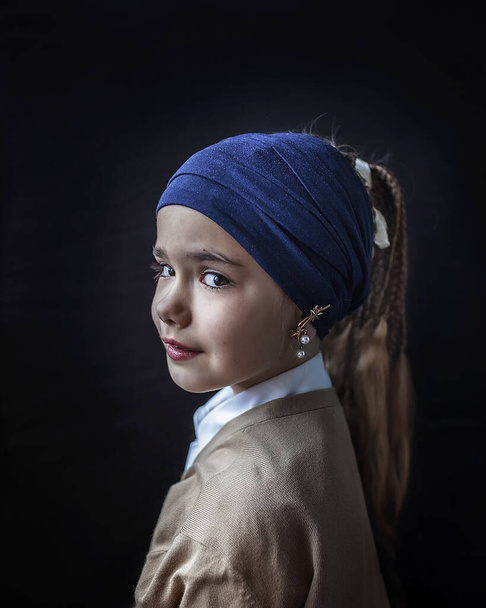 Retrato de cerca de la linda niña de 7-8 años en bufanda azul en el cabello y pendientes de perlas, belleza y arte, esquema clásico de luz, fondo oscuro clave
 - Foto, imagen