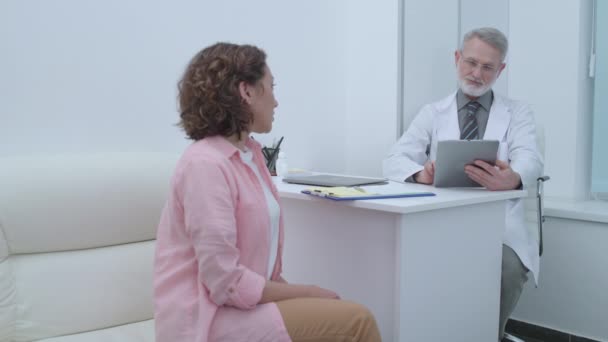 Doctor listening to woman, typing on tablet, patient talking to psychologist - Video