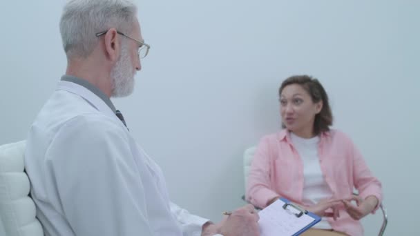 Senior psychologist listening to female patient, making notes, mental health - Video