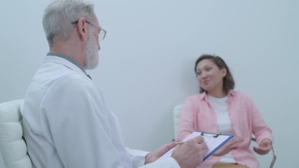 Glad female patient shaking doctor's hand, leaving office, solution of problems - Felvétel, videó
