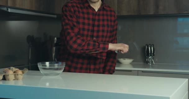 A funny hipster man is about to cook some eggs in his kitchen. He jumps into view and starts spinning and throwing a spatula. Slow motion shot. - Video, Çekim