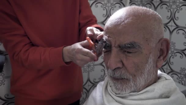 Nahaufnahme eines 80-jährigen älteren türkischen muslimischen Mannes, dessen Augenbrauen in seinem Vintage-Badezimmer aus den 1980er Jahren geschnitten wurden - Filmmaterial, Video
