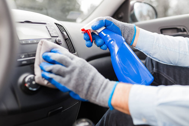 Close up of man hands using microfiber cloth and spray bottle while cleaning car interior. - Fotografie, Obrázek