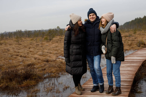 a guy and two girls walk in nature. Friends laugh and smile - Photo, Image