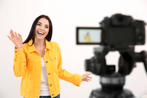Young blogger recording video on camera against white background - Fotó, kép