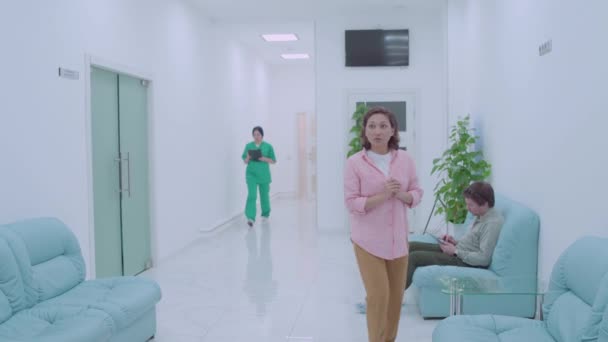 Doctor talking to sad woman in hospital hallway, bad news, serious illness - Filmagem, Vídeo