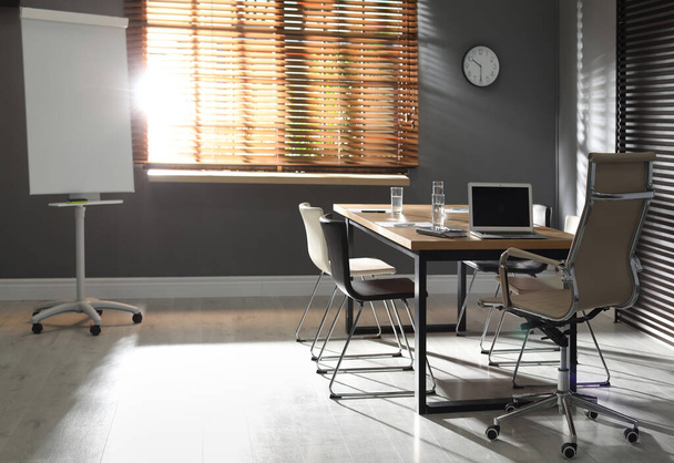 Interior de escritório elegante com mesa de madeira e flipchart
 - Foto, Imagem