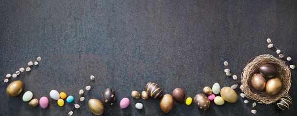 Colorful Easter eggs banner with willow branches on rustic background. Top view with copy space - Fotoğraf, Görsel
