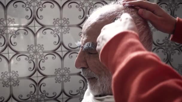 80 Jahre alter türkisch-muslimischer Mann lässt sich in seinem Vintage-Badezimmer aus den 1980er Jahren die Haare schneiden - Filmmaterial, Video