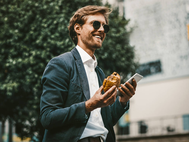 Happy young freelancer having a lunch on the go. - Foto, Imagen