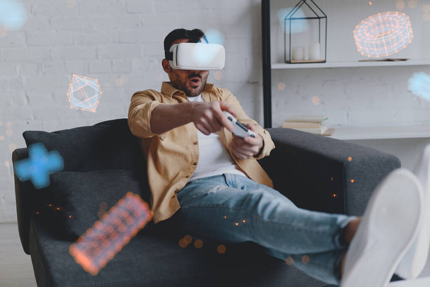 Young smiling man in VR glasses playing game using joystick, virtual reality - Foto, afbeelding