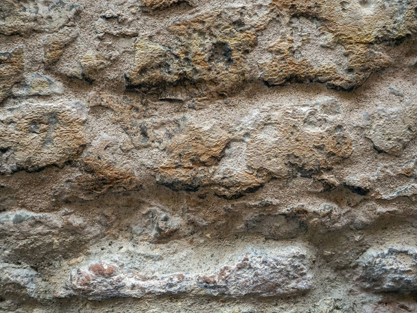 Ściana wykonana jest z dużych kamieni. Kamienna ściana pokryta jest kurzem. Historyczne tło kamienia. - Zdjęcie, obraz
