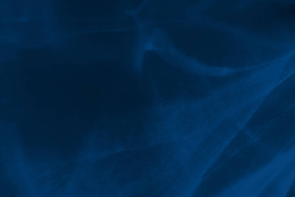 Trendy blauw gekleurde laag contrast abstracte achtergrond met licht en schaduwen bijtende effect. Licht gaat door een glas. Water achtergrond. 2020 jaar kleur trend - Foto, afbeelding