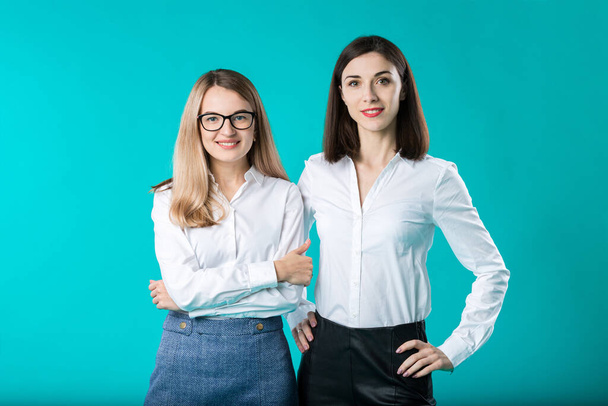 Portret van twee vrouwen in kantoorkleding. Leuke, aantrekkelijke zakenvrouwen. Team van twee lachende zakenvrouwen die poseren. twee jonge vrouwelijke collega 's in een studio. - Foto, afbeelding