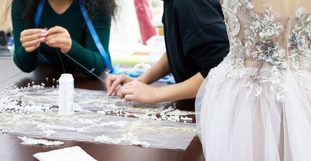 Mannequin with a wedding dress is in the tailors shop. Dressmaker working in atelier. - Fotó, kép