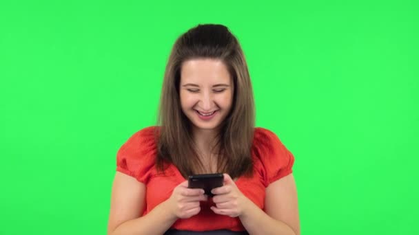 Portrait of cute girl texting on her phone. Green screen - Záběry, video