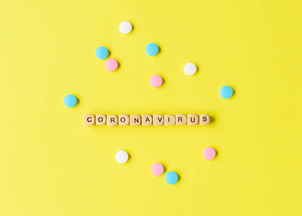 Coronavirus concept. Pills and beads with letters on yellow background. Contagious virus concept. - Photo, image