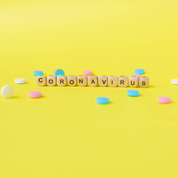 Coronavirus concept. Pills and beads with letters on yellow background. Contagious virus concept. Square format. - 写真・画像