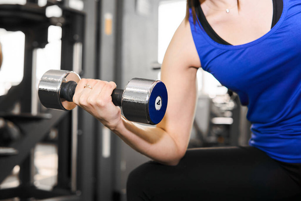 hand of a woman performing dumbbell exercise for biceps at the gym - Foto, Imagem
