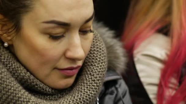 Mooie dame in winterjas rijdt in metro rijtuig en kijkt naar telefoon scherm - Video