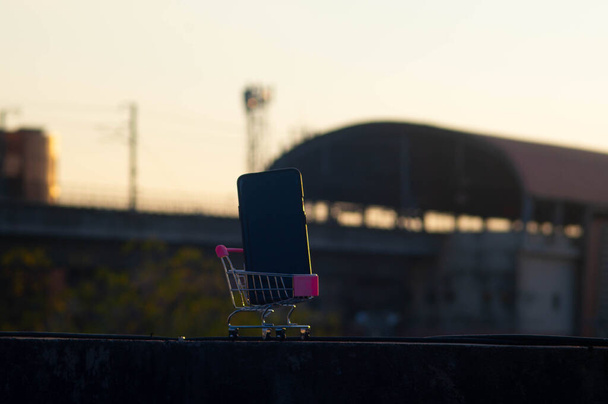Ένα τρόλεϊ αποσκευών παιχνιδιών από μέταλλο και πλαστικό που μεταφέρει ένα κινητό τηλέφωνο - Φωτογραφία, εικόνα