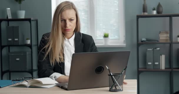 Confident mature lady working on laptop at office - Кадри, відео