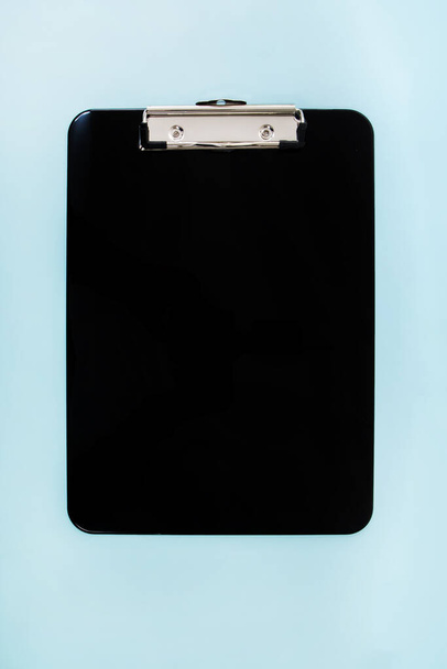 Close up view of a Black clipboard  over blue background. - Photo, Image