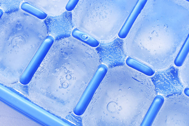 A blue plastic ice cube tray with frost on it isolated over a white  background, Stock image