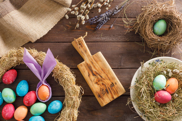 Still life many colorful easter eggs on a wooden background. Rustic. Decoration from natural fabrics and herbs. Easter celebration concept. Copy space. Flat lay - Photo, Image