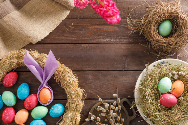 Natura morta molte uova di Pasqua colorate su uno sfondo di legno. Rustico. Decorazione da tessuti naturali ed erbe. Concetto di celebrazione pasquale. Ricevuto. Posa piatta
 - Foto, immagini
