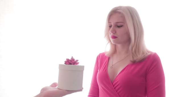 Verveeld blond in rode jurk ontvangt een geschenk van de mannen handen, enthousiast, teleurgesteld opent de doos en gooit de doos opzij - Video