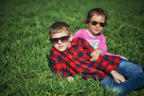 Niños graciosos en un paseo por el campo. Hermano y hermana jugando en la hierba
 . - Foto, imagen