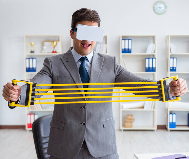 VRメガネをかけた伸縮式エクササイズで運動するビジネスマン - 写真・画像