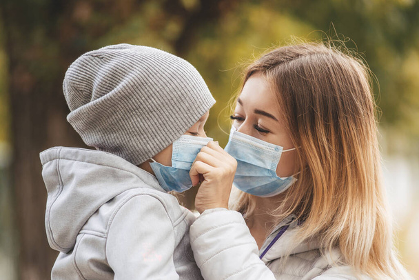 Mädchen mit Kind steht in Italien mit einer medizinischen Schutzmaske auf der Straße. Coronovirus in Europa - Foto, Bild