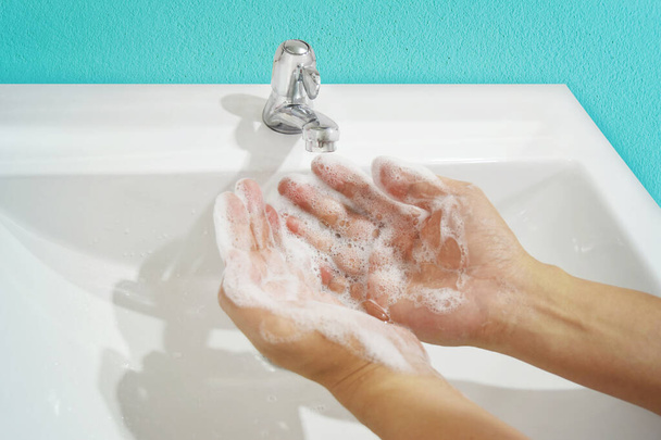 Το άτομο πλένει τα χέρια του με νερό και σαπούνι στο νεροχύτη. Προστατέψτε τη λοίμωξη από το coronavirus (covid 19). - Φωτογραφία, εικόνα