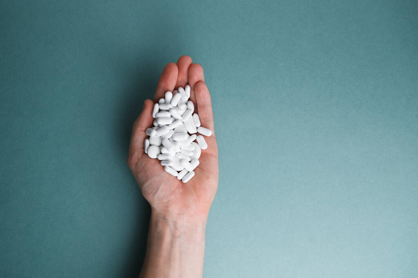 White tablets on a blue background are isolated. Hand with a tablet. A pile of pills in the open palm. Virus protection and 2019-ncov.  - Photo, Image