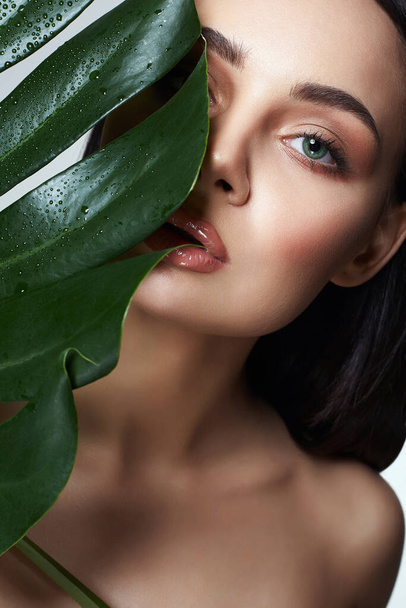 beautiful girl in palm leaves. Beautiful young woman with Make-up. Beauty Portrait. Natural cosmetics - Foto, Bild