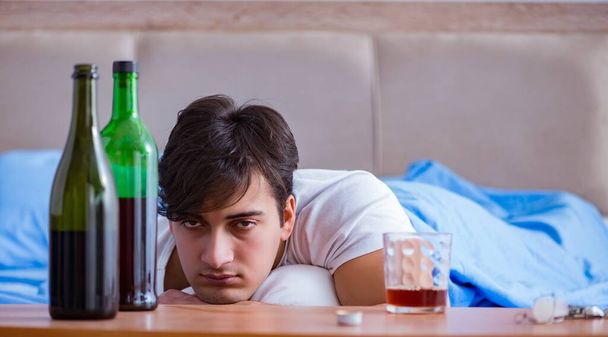 Mies alkoholisti juo sängyssä menossa läpi hajottaa masennus - Valokuva, kuva