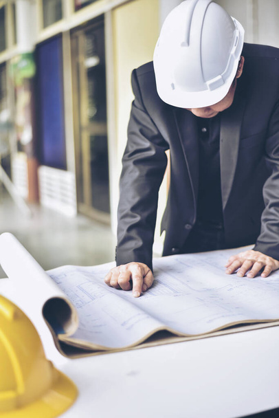 Image of engineer checking blue print.Young architect man or engineer working on his plane project at site construction work. - Photo, Image