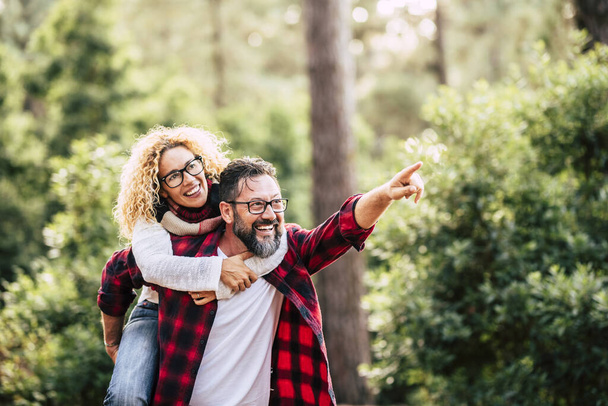 Happy cheerful adult beautiful couple have fun together and joy in the wood forest - concept of love and friendship with people - travel and environment  man and woman smiling - Photo, Image