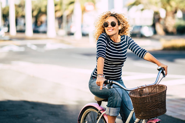 Piękne i wesołe dorosłe młoda kobieta cieszyć się jazda na rowerze w słonecznej miejskiej rozrywki na świeżym powietrzu w mieście - szczęśliwych ludzi portret - modne kobiety na zewnątrz zabawy - Zdjęcie, obraz
