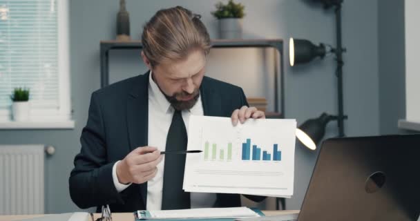 Confident man showing financial graphs during video chat - Video, Çekim
