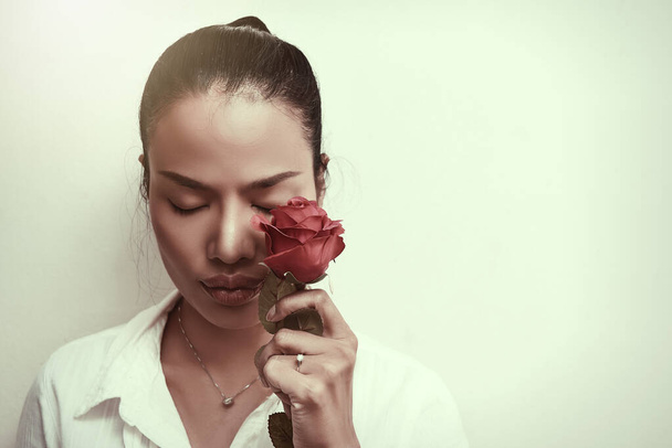 Beautiful young woman closing eyes with red roses. - Photo, Image