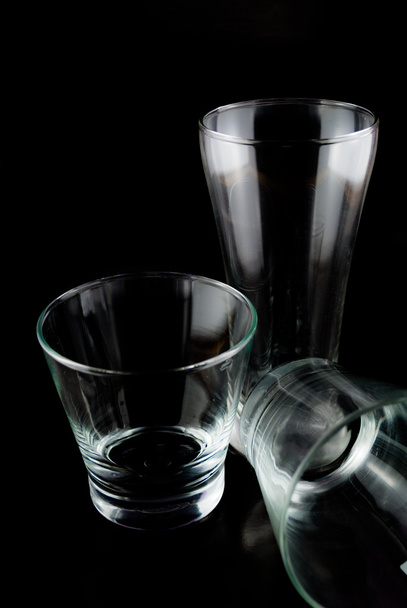 Пустые бокалы для виски на отражающей поверхности на черном фоне
 - Фото, изображение