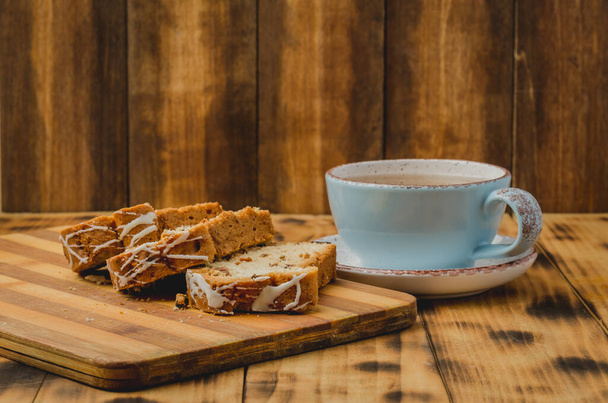 Πρωινό με φλιτζάνι τσάι και αρτοσκευάσματα φέτες σε ξύλινη σανίδα σε ένα τραπέζι. Επιλεκτική εστίαση - Φωτογραφία, εικόνα