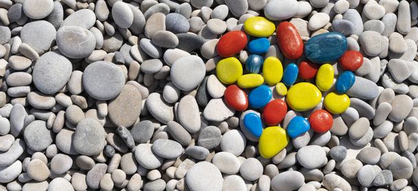 Werelddag van het autisme. Top uitzicht op witte strand stenen met kleurrijke hart gemaakt van geschilderde stenen - Foto, afbeelding