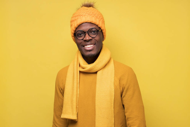 Fiatal afrikai férfi sárga pulóver kalap és sál mosolyog a kamerába - Fotó, kép